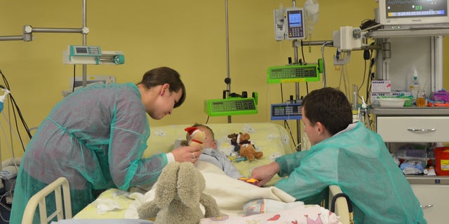 In this photo taken by Magdalena Oberc, the spokeswoman of the childrens hospital in Krakow, Poland, on Thursday, Dec. 4, 2014, a 2-year-and-4-months-old Adam is seen with his mother Paulina, his father Mateusz and a teddy bear, just a few days after he was brought to the hospital with his temperature at only 12.7 C (55 F) and his heart beating once every few dozen seconds after being found outdoors in sub-freezing temperature on Sunday morning with almost no clothes on. Dr. Janusz Skalski, a heart surgeon at the hospital, said its a miracle that the boy is showing no negative signs from the hours that he spent in such low temperature. (AP Photo/Magdalena Oberc, Krakow Childrens Hospital spokeswoman)