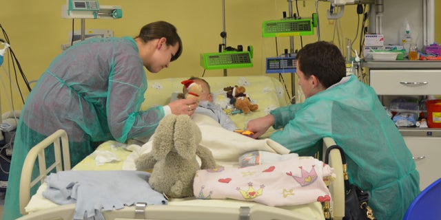 In this photo taken by Magdalena Oberc, the spokeswoman of the childrens hospital in Krakow, Poland, on Thursday, Dec. 4, 2014, a 2-year-and-4-months-old Adam is seen with his mother Paulina, his father Mateusz and a teddy bear, just a few days after he was brought to the hospital with his temperature at only 12.7 C (55 F) and his heart beating once every few dozen seconds after being found outdoors in sub-freezing temperature on Sunday morning with almost no clothes on. Dr. Janusz Skalski, a heart surgeon at the hospital, said its a miracle that the boy is showing no negative signs from the hours that he spent in such low temperature. (AP Photo/Magdalena Oberc, Krakow Childrens Hospital spokeswoman)