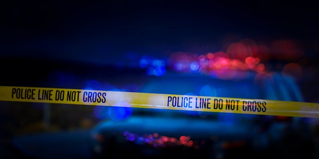 عکس استوک خط پلیس "رد نشوید" نوار احتیاط با یک ماشین پلیس غیرفعال با آژیرهای قرمز و آبی چشمک زن.