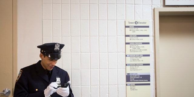 File photo - A New York Police Department graduate video chats on his smartphone backstage before his induction ceremony at Madison Square Garden in New York, December 27, 2013. (REUTERS/Carlo Allegri)