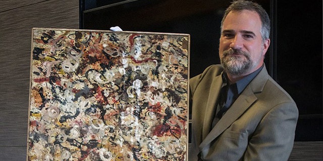 Auctioneer Josh Levine holds a painting that he believes is an original Jackson Pollock and that will go up for auction June 20.