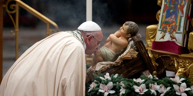 Dec. 31, 2014: Pope Francis kisses a statue of the baby Jesus as he arrives to celebrate the new year's eve vespers Mass in St. Peter's Basilica at the Vatican. (AP)