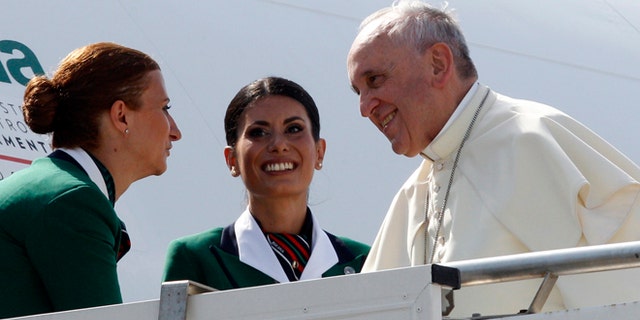Aug 13, 2014: Pope Francis is welcomed by two hostesses as he boards a plane to South Korea, at Rome's Fiumicino international airport. (AP)