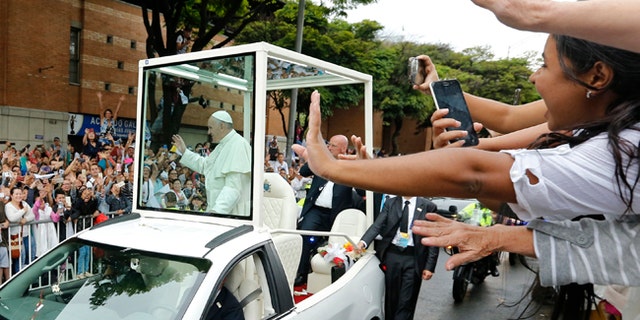 People wave to Pope Francis in the popemobile in Medellin, Colombia, Saturday, Sept. 9, 2017.