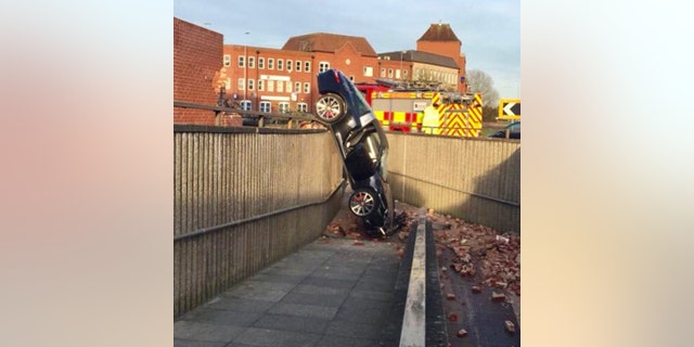 The car landed on top of a 10-foot-tall barrier wall and tipped onto its nose.
