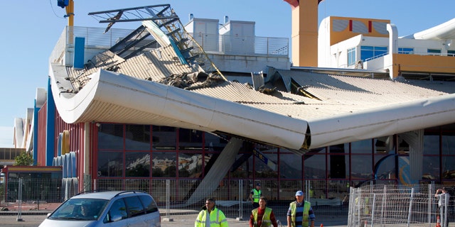 Oct. 24, 2011: Workers walk in front of the damaged building of Faro airport.