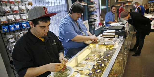 Employees roll joints behind the sales counter at Medicine Man marijuana dispensary in Denver. (AP)