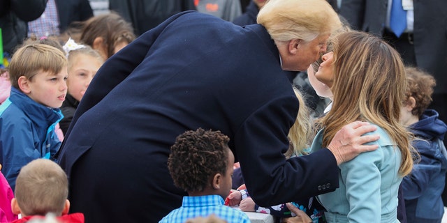 President Donald Trump leans over to kiss first lady Melania Trump, right seated, during the annual White House Easter Egg Roll on the South Lawn of the White House in Washington, Monday, April 2, 2018. (AP Photo/Pablo Martinez Monsivais)