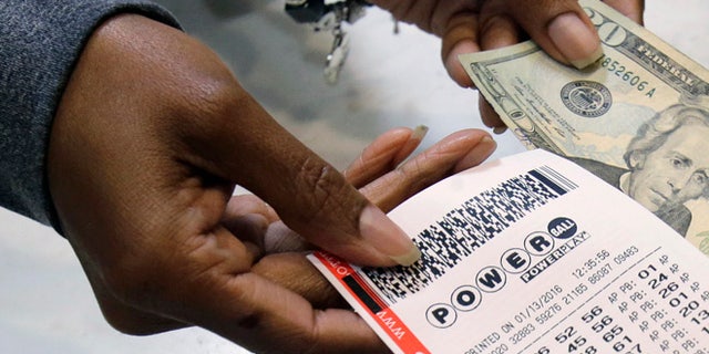 In this Jan. 13, 2016 file photo, a clerk hands over a Powerball ticket for cash at Tower City Lottery Stop in Cleveland. Powerball estimates that its jackpot for the May 4, 2016