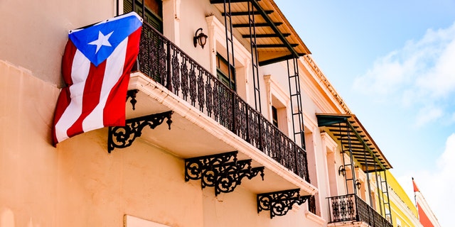 Colorful house  facades along a street in Old San Juan, Puerto Rico with a Puerto Rican flag hanging down from one of the balconies