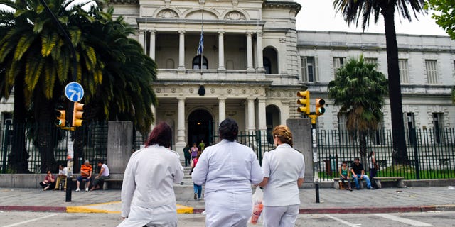 Three doctors enter the military hospital in Montevideo, Uruguay, Sunday, Dec. 7, 2014.
