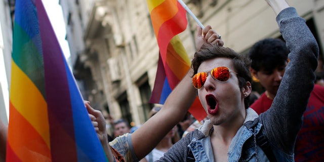 FILE - In this Sunday, June 28, 2015 file photo, participants of a Pride Week event in Istanbul, chant slogans after police used a water canon to disperse them. For several years, Pride Week in Istanbul attracted tens of thousands of participants, making it one of largest gatherings celebrating gay, lesbian and transgender rights and diversity in the Muslim world. That changed suddenly in 2015, when authorities, citing security concerns, banned gay and trans-gender pride events chasing away shocked participants trying to converge on central Taksim Square with tear gas and water cannons. (AP Photo/Emrah Gurel, File)