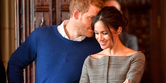 Prince Harry whispers to Meghan Markle as they watch a performance by a Welsh choir in the banqueting hall during a visit to Cardiff Castle in Cardiff, Britain, January 18, 2018.