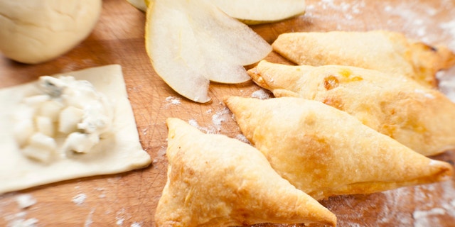 Triangle wraps of puff pastry with blue cheese and pear. Baked, fresh and surrounded with raw ingredients