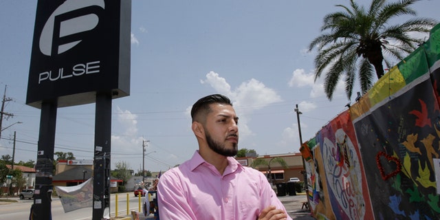 In this Tuesday, May 30, 2017 photo, Marco Quiroga, who works to support LGBTQ and social-justice causes in central Florida, reflects in front of one of the memorials at the Pulse Nightclub in Orlando, Fla. A year after the Pulse Nightclub shooting, the city's gay Latinos are trying to build up their community by forming support groups, seeking seats at the tables of power and creating a foundation to champion gays and Latinos. (AP Photo/John Raoux)