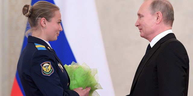 Putin presents flowers to Sgt. Tatyana Kovaleva in the Kremlin on Thursday.