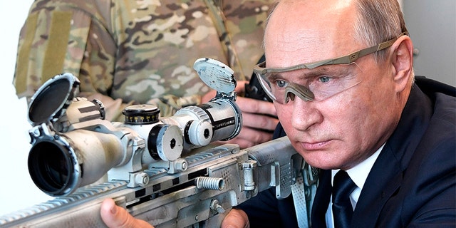 Russian President Vladimir Putin aims a sniper rifle during a visit to the Patriot military exhibition center outside Moscow, Russia.