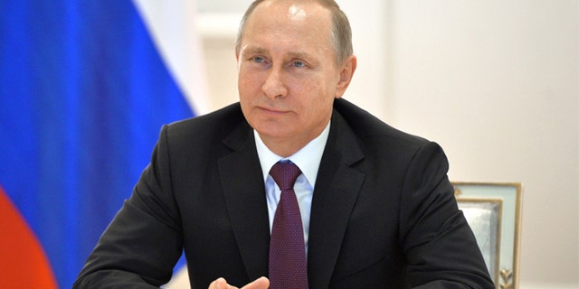 Russian President Vladimir Putin smiles during a live video link with members of Russian Geographical Society expedition to the Southern Pole in Moscow's Kremlin, Russia on Friday, Dec. 26, 2014.