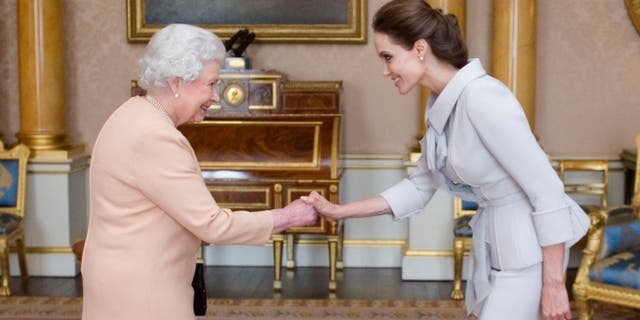 October 10, 2014. Angelina Jolie, right, is presented with the Insignia of an Honorary Dame Grand Cross of the Most Distinguished Order of St Michael and St George by Queen Elizabeth II at Buckingham Palace, London.