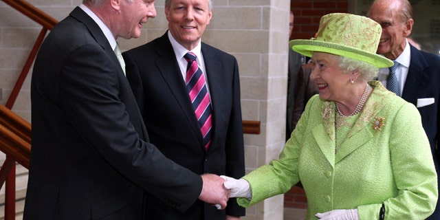 June 27, 2012: Britain's Queen Elizabeth II shakes hands with Northern Ireland Deputy First Minister and former IRA commander Martin McGuinness watched by First minister Peter Robinson, centre, at the Lyric Theatre in Belfast, Northern Ireland.