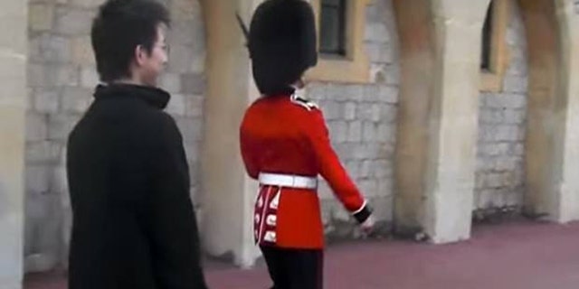 The tourist was mocking the soldier by walking alongside of him.