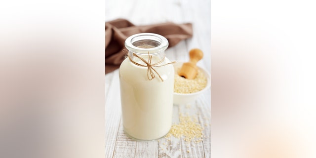 Quinoa milk in glass bottle on wooden background