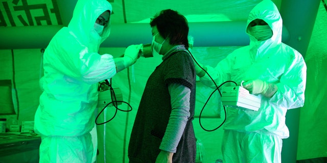 Medical staff use a Geiger counter to screen a woman for possible radiation exposure at a public welfare centre in Hitachi City, Ibaraki, March 16, 2011, after she evacuated from an area within 20km (12.4 miles) radius of the Fukushima Daiichi nuclear plant. The woman was tested negative for radiation exposure. Radiation has been released into the atmosphere at the Fukushima Daiichi nuclear plant run by Tokyo Electric Power Co. on the country's northeast coast, which was badly damaged after a massive earthquake and tsunami on March 11.