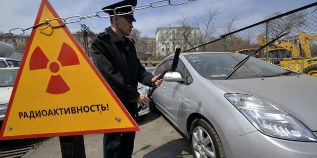 A customs officer measures the radiation level of an automobile delivered from Japan, in Russia's far eastern city of Vladivostok April 14, 2011. About 300 cars and other vehicles are delivered from neighbouring Japan to the port. Radioactive background has been revealed in 49 vehicles lately. These machines will be kept in the port until the Russian Federal Service on Customers' Rights makes a decision on their fate, Russian customs officers said. The sign reads "Radioactivity".