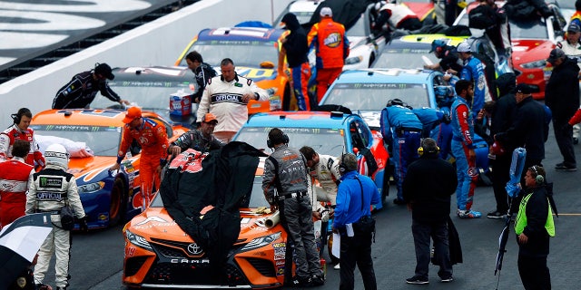Crews cover the cars as rain falls during a NASCAR Cup Series auto race, Sunday, April 15, 2018, in Bristol, Tenn. (AP Photo/Wade Payne)
