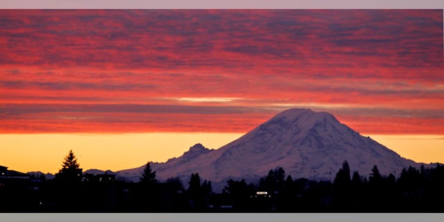 Mount Rainer, a 14,411-foot stratovolcano, is seen at dawn during a colorful sunrise Tuesday, Dec. 13, 2011, from Seattle, some 50 miles away. Generally clear skies are expected through Tuesday in the area, with an increasing chance of showers coming Wednesday, with highs in the low 40's through the week. (AP Photo/Elaine Thompson)