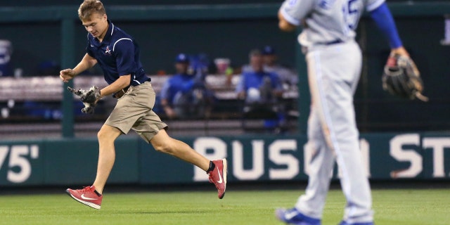 A Busch Stadium grounds crew members carries a small cat that had run across the outfield.