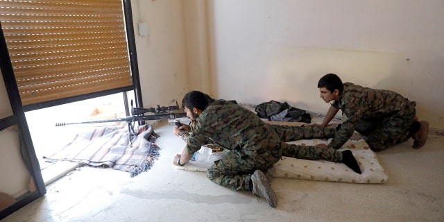 Fighters of Syrian Democratic Forces take up position inside a building opposite the National Hospital where ISIS fighters were holed up.