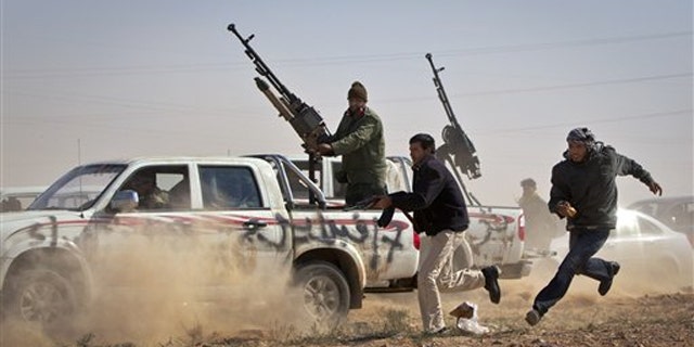 Rebel fighters shoot the tires out of a vehicle, unseen, belonging to Muammar al-Qaddafi's forces as it speeds through the rebel front line east of Brega, Libya, April 3.
