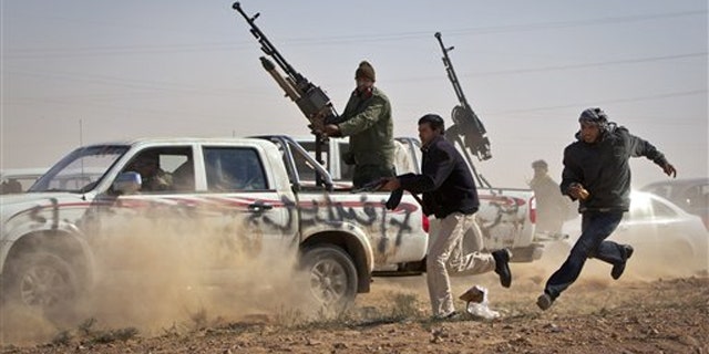 Rebel fighters shoot the tires out of a vehicle, unseen, belonging to Muammar al-Qaddafi's forces as it speeds through the rebel front line east of Brega, Libya, April 3.