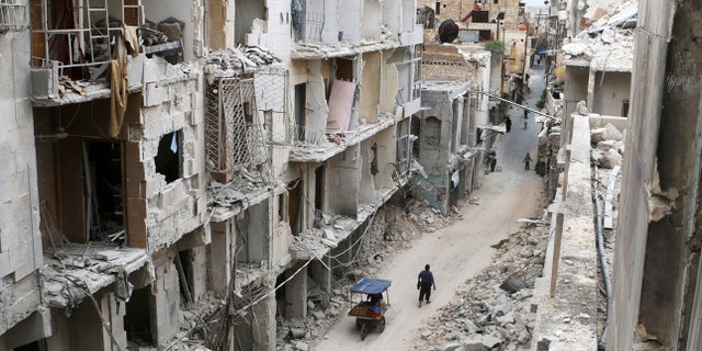 Residents walk near damaged buildings in the rebel held area of Old Aleppo, Syria May 5, 2016. REUTERS/Abdalrhman Ismail/File Photo - RC1FE5D0C050