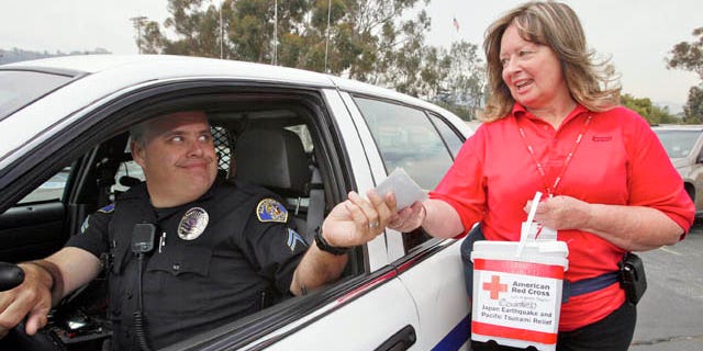 March 14: Alhambra Police officer Kevin Lang drives in to drop checks and cash donated by his station police officers to American Red Cross volunteer Cathy Sproule for the Japan Earthquake and Pacific Tsunami Relief Fund at the Rose Bowl in Pasadena, Calif. (AP)