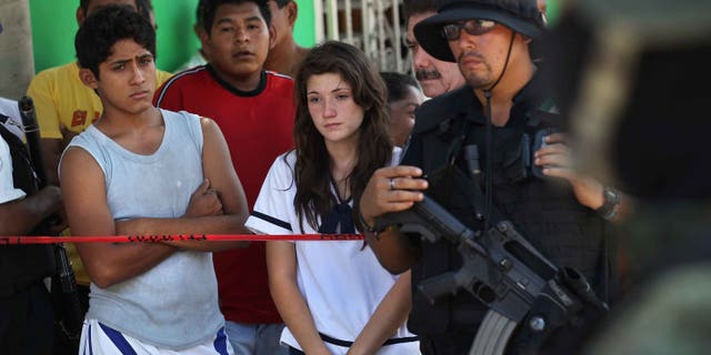 ACAPULCO, MEXICO - MARCH 02: Family members, neighbors and police gather at the site of a suspected drug-related double execution on March 2, 2012 in Acapulco, Mexico. Drug violence has surged in the coastal resort in the last year, making Acapulco the second most deadly city in Mexico after Juarez. One of Mexico's top tourist destinations, Acapulco has suffered a drop in business, especially from foreign tourists, due to the violence. Toursim accounts for about 70 percent of the economy of Acapulco's state of Guerrero and 9 percent of Mexico's economy. (Photo by John Moore/Getty Images)