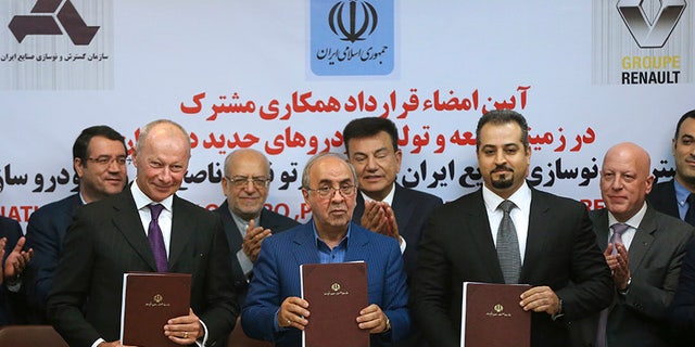 Chief Competitive Officer of Groupe Renault Thierry Bolloré, left, Chairman of Industrial Development and Renovation Oraganization of Iran, IDRO, Mansour Moazami, center, and Negin Group CEO Kourosh Morshed Solouk join shows documents to media after signing a deal in Tehran, Iran, Monday, Aug. 7, 2017. Iran signed the country's biggest-ever car deal with French multinational automobile manufacturer Groupe Renault on Monday to produce 150,000 cars, beginning in 2018. (AP Photo/Vahid Salemi)