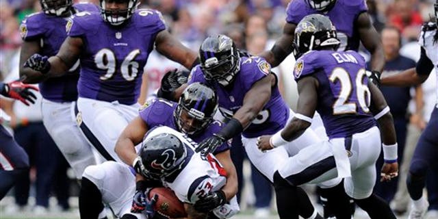 Houston Texans running back Arian Foster, bottom, is tackled by a pack of Baltimore Ravens defenders in the first half of an NFL football game Sunday, Sept. 22, 2013, in Baltimore. (AP Photo/Nick Wass)
