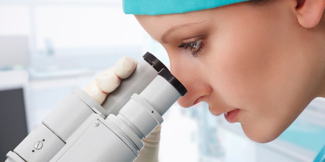 Woman scientist working with microscope at laboratory
