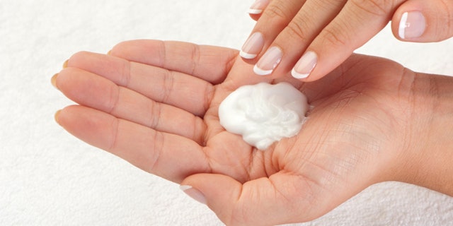 Beautiful female hand applying moisturiser close up