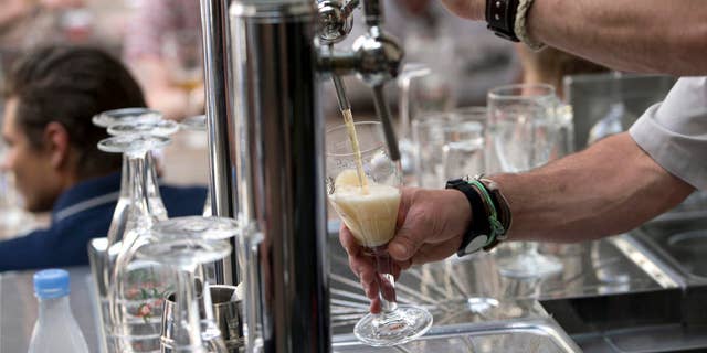 A worker pours a glass of beer for customers at the Halve Maan Brewery in Bruges, Belgium.