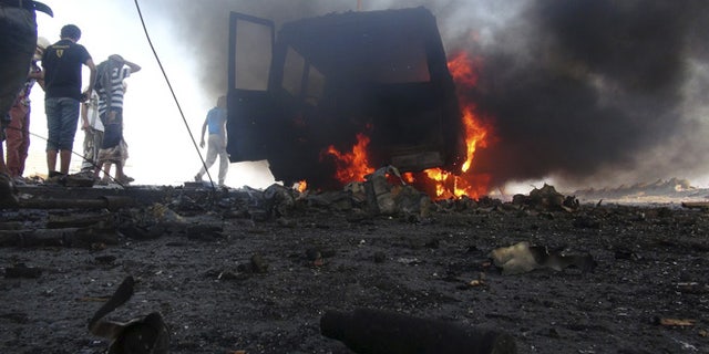 March 26, 2015: People watch a vehicle which belonged to rebels burn during clashes in Aden.