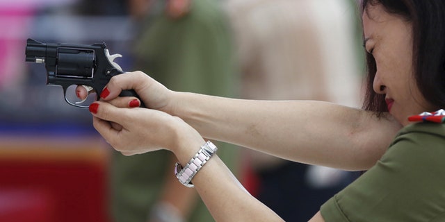 A policewoman demonstrates a Vietnamese-made pistol during celebrations to commemorate the 70th anniversary of the establishment of the Vietnam Public Security police force in Hanoi, Aug. 18, 2015.