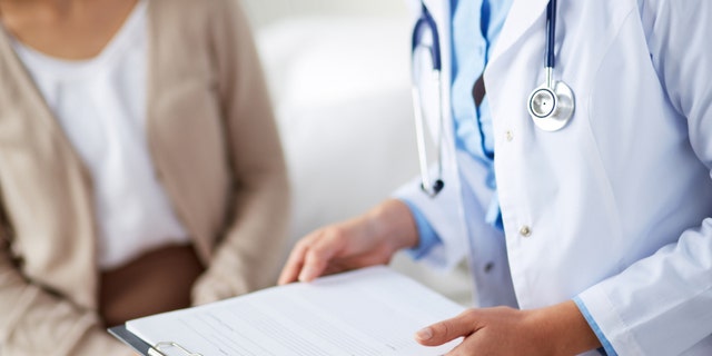 Female doctor holding application form while consulting patient