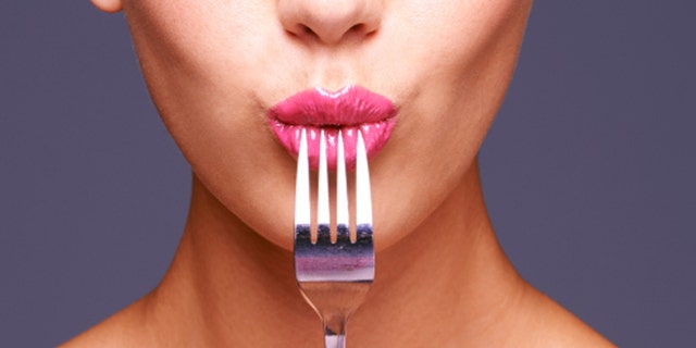 Shot of a beautiful young woman biting on a fork