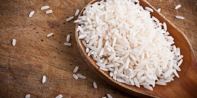 Rice with wooden spoon on wooden table.