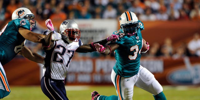 Miami Dolphins running back Ricky Williams (R) tries elude New England Patriots defender Kyle Arrington as Dolphins end Anthony Fasano (L) blocks in the first half during their NFL football game in Miami, Florida October 4, 2010. REUTERS/Hans Deryk (SPORT FOOTBALL) - RTXT1XF