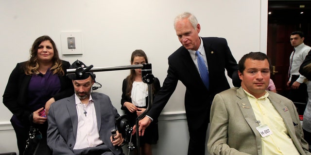 Sen. Ron Johnson, R-Wis., back right, reaches for the arms of ALS sufferers Frank Mongiello, left, and Matthew Bellina, during a news conference following the passage of the Right to Try Act at the Capitol in Washington.