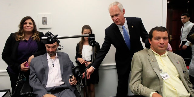 Sen. Ron Johnson, R-Wis., back right, reaches for the arms of ALS sufferers Frank Mongiello, left, and Matthew Bellina, during a news conference following the passage of the Right to Try Act at the Capitol in Washington.